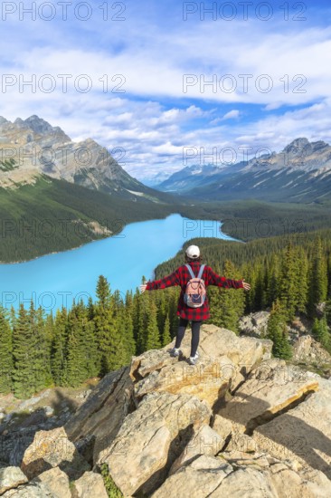 Female hiker with a backpack standing on a rocky cliff, enjoying the stunning panoramic view of