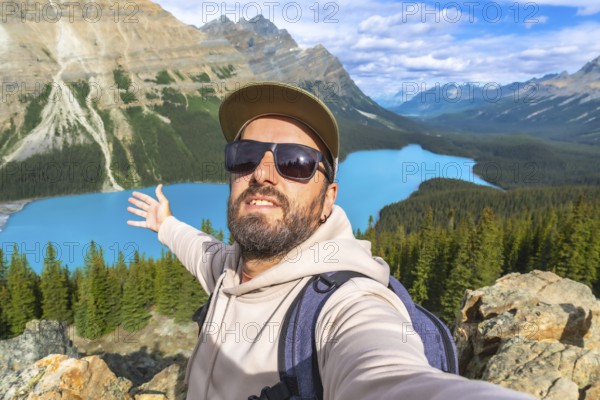 Hiker taking a selfie with outstretched arms, embracing breathtaking turquoise waters of peyto