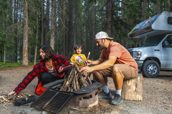 Family enjoying a delightful camping trip, gathering around a crackling campfire beside their cozy