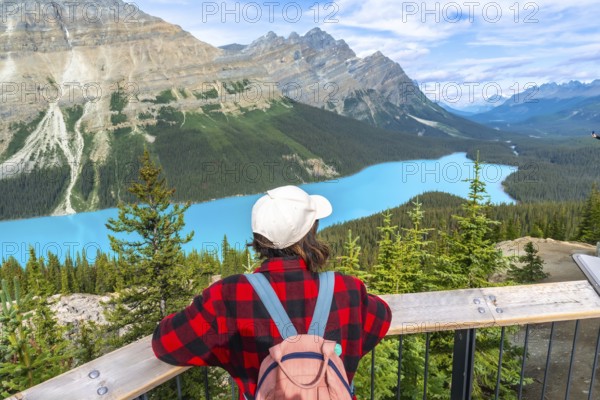 Female tourist with a backpack admiring the stunning turquoise waters of peyto lake, framed by the