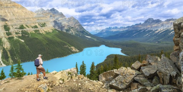 Tourist with backpack is enjoying the breathtaking panoramic view of the turquoise peyto lake and