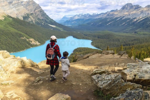 Mother and child admiring the stunning turquoise waters of peyto lake from a scenic viewpoint in