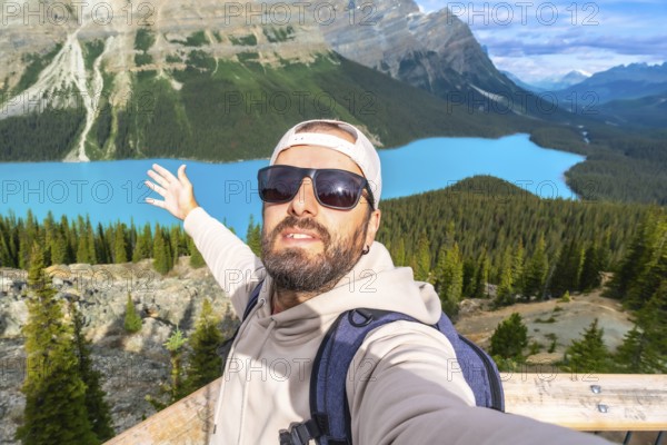 Tourist with a backpack and sunglasses taking a selfie at the scenic viewpoint of peyto lake in