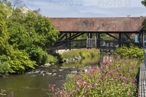 Covered footbridge over the Kronach river, hospital bridge, Blooming flowers on the shore, Kronach,