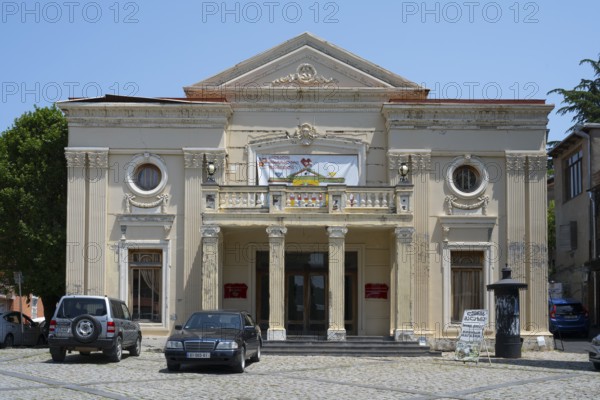 Neoclassical theatre building with columns and cars in the foreground on a sunny day, theatre,