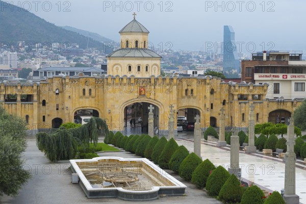 Historic church with yellow tone and modern city in the background against mountain backdrop,