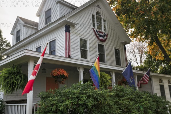 Typical American house in autumn, white wooden house with veranda, guest room, rainbow flag,