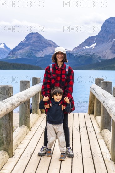 Smiling mother and son embracing the stunning scenery of turquoise bow lake and surrounding