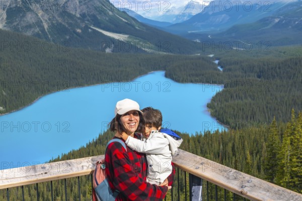 Mother holding her son while admiring the stunning turquoise waters of peyto lake, surrounded by