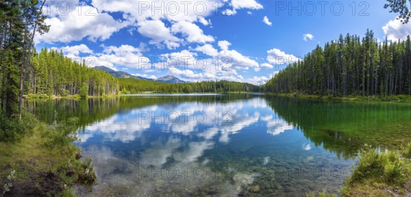 Breathtaking panoramic view of pristine herbert lake reflecting a vibrant blue sky with fluffy