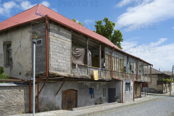 An old, rustic building with a dilapidated state and wooden veranda under a clear blue sky,