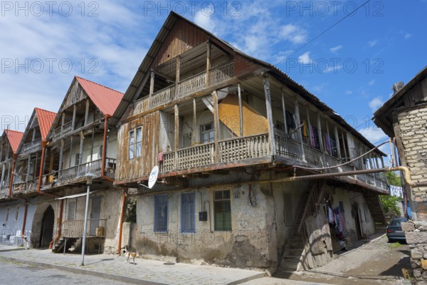 Historic wooden house with veranda under a blue sky, showing traditional architecture, traditional