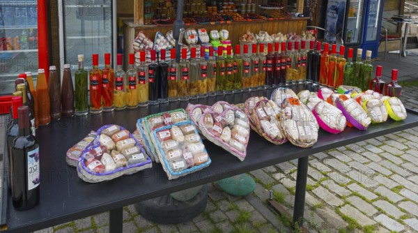 Diverse selection of spices and bottles at a traditional market stand, chacha with colorful fruits,