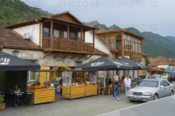 Cosy marketplace with cafes and shops framed by mountains under a cloudy sky, houses on Mtskheta
