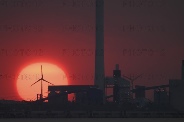 Sunset behind industry and wind turbines, near Jade-Weser Port, intense red in the sky View over