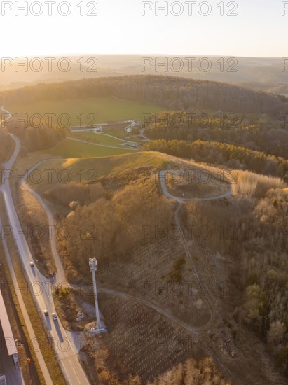 Hilly landscape with roads and dense forest in the light of sunset, future PV building on old