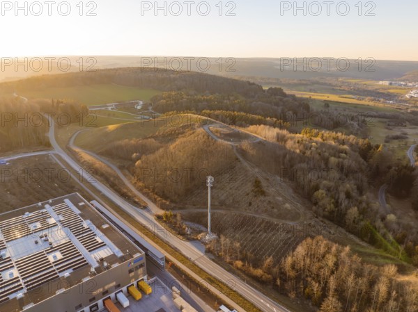 Telecommunication tower over hilly landscape and industrial buildings in the evening light, future