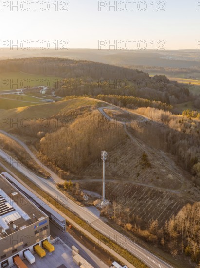 Hilly landscape with forest and telecommunications tower at sunset, future PV building on old