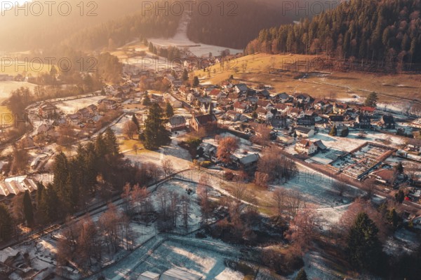 Expansive view of a village with snow-covered roofs surrounded by hills and forests, Enzklösterle,