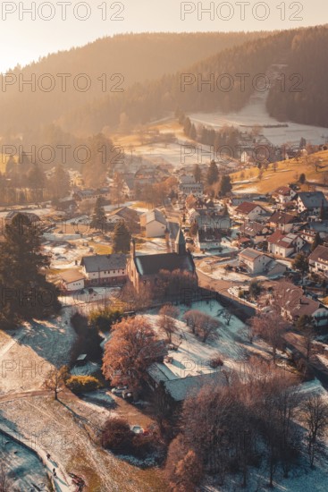 Idyllic view of a village with a central church surrounded by snow-covered houses and hills,