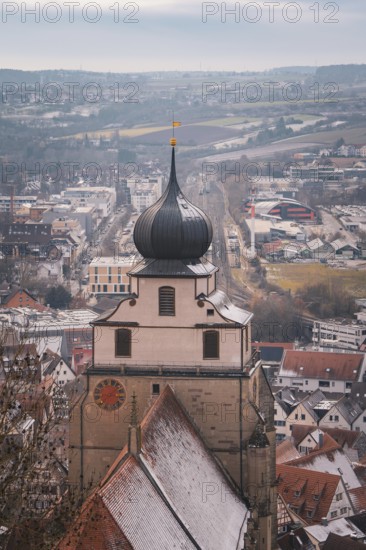 View of a church tower in front of a snow-covered city panorama with vast fields, Herrenberg,
