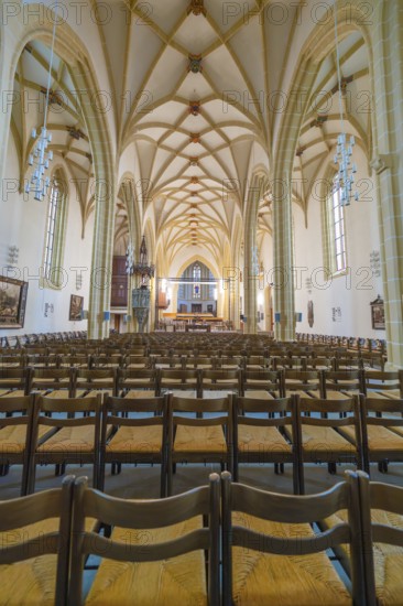 Symmetrical view along the rows of benches in the nave with Gothic columns and high ceilings,