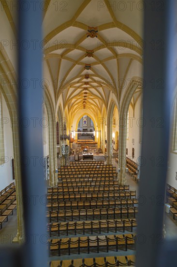 Symmetrical view of a church interior with altar and chairs, characterized by Gothic style,