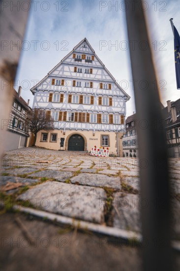 Large half-timbered house with symmetrical façade and grid in the foreground in a historic old