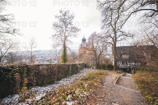 Winter trail with a view of a church tower and landscape, surrounded by bare trees, Herrenberg,
