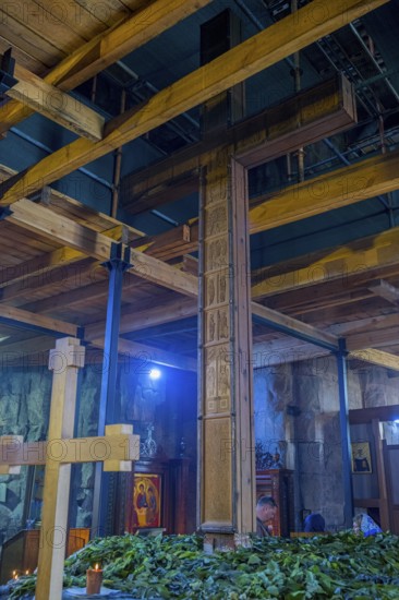Interior with wooden cross, wooden beams and plants under artificial light, Javari Monastery,