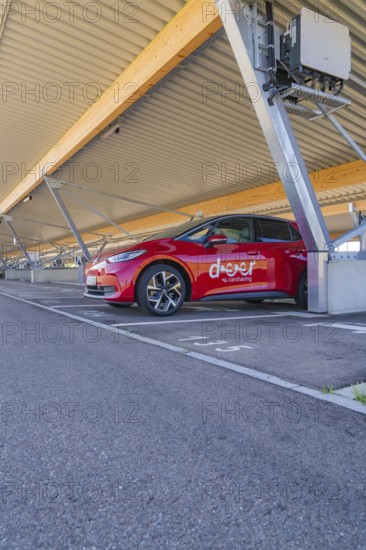 Red electric car parked under a modern roof in a parking lot, ID3, Deer e-Carsharing, Germany