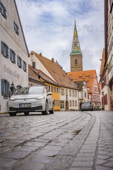 Paved alley in charming old town district with church tower, ID3, deer e-car sharing, Germany