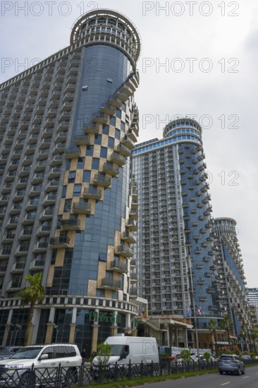 Modern skyscrapers with spiral balconies dominate the city skyline under cloudy sky, Orbi Sea