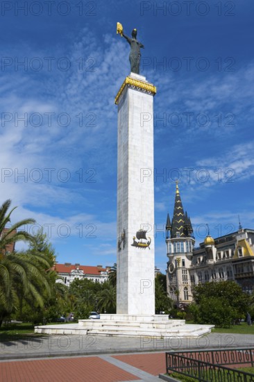 Tall column with statue in a square next to a magnificent building and tower, statue of Medea,