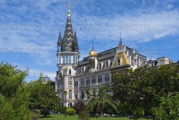 Castle-like building with tall tower and green garden under blue sky, Astronomical Clock, Black