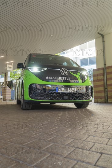 Green VW from the front in an urban, modern environment, Deer E-Mobility Shuttle Service, Calw,