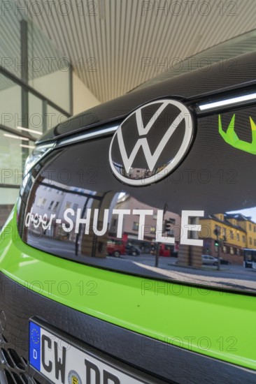 Front view of a green VW with sign in an urban environment, Deer E-Mobility Shuttle Service, Calw,