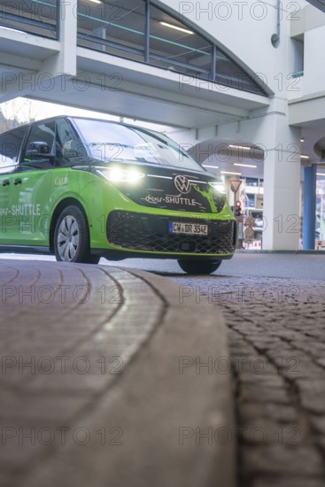 Green Volkswagen shuttle in front of a modern building in an urban area, Deer E-Mobility Shuttle