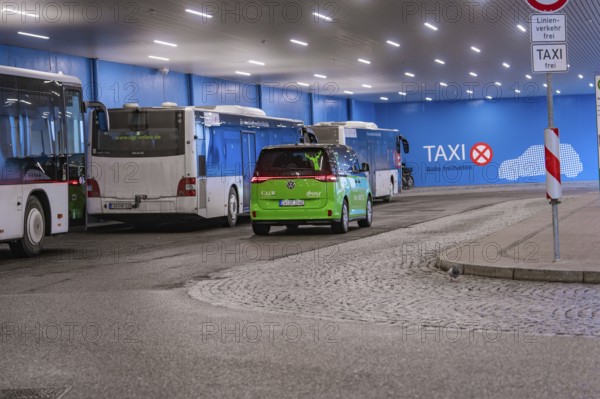 Bus station with green shuttle and taxi signs, urban scene at night, Deer E-Mobility Shuttle