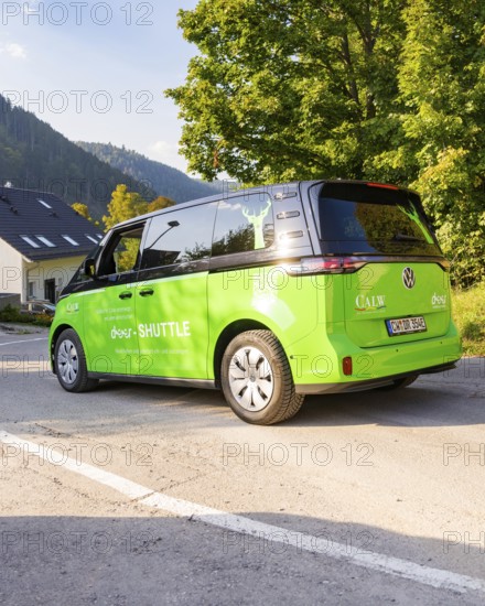 Green car on road in picturesque landscape with mountains in the background, Deer E-Mobility