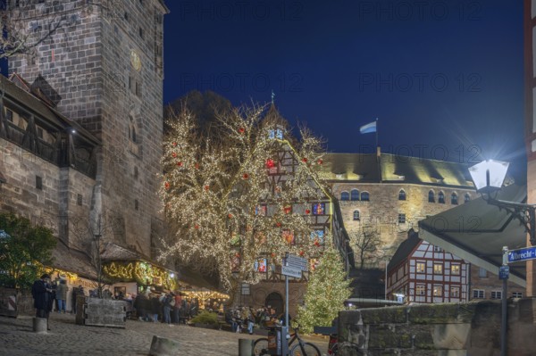Christmassy illuminated square with the historic Pilate House with advent calendar, in the evening