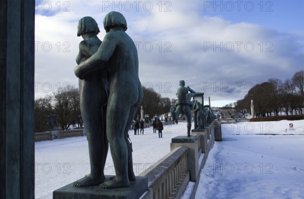 Sculptures on a snowy bridge, people walking, cold winter atmosphere, Vigeland sculpture park Oslo