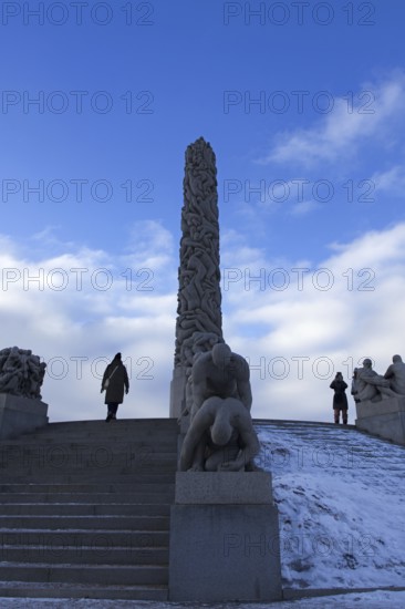 Monolith and sculptures on snowy stairs. People standing and admiring, Vigeland Sculpture Park Oslo