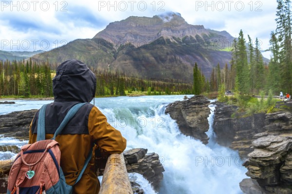 Backpacker enjoying the breathtaking view of athabasca falls cascading through the rugged landscape