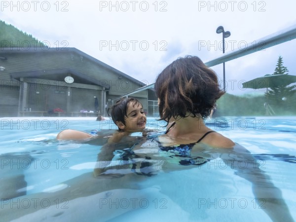 Mother and son are smiling while swimming in the miette hot springs located in jasper national
