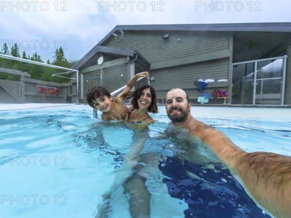 Happy family taking a selfie while bathing in miette hot springs, the hottest natural hot springs