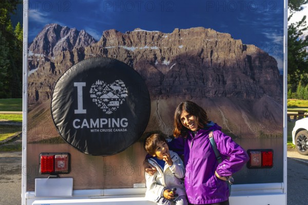 Mother and son posing happily in front of their rv, featuring a large i love camping graphic and a