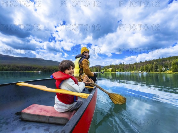 Father and son are paddling a canoe on beautiful maligne lake in jasper national park, alberta,
