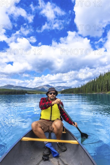 Tourist paddling a canoe in maligne lake under a beautiful cloudy sky, enjoying the turquoise water
