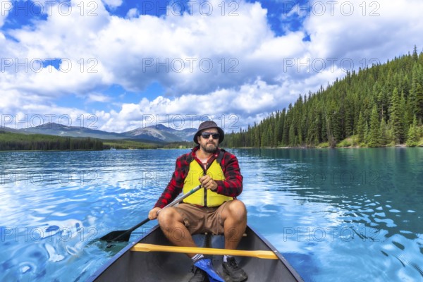 Tourist paddling a canoe on turquoise maligne lake with spirit island in the distance, enjoying the